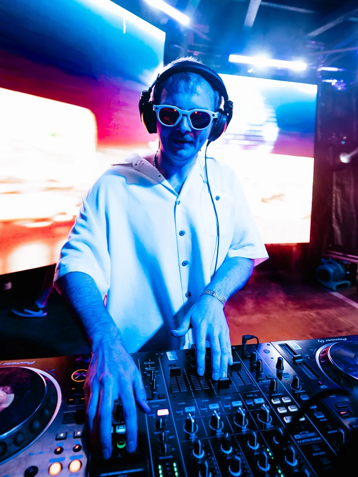 TITAN wearing headphones and sunglasses, mixing with both hands on the decks